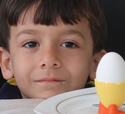 Porträtbild des Knaben Esat mit einem Ei im Eierbecher daneben