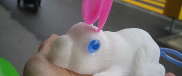 ein weisser Hüpfhase mit rosa Ohren auf einer Hand