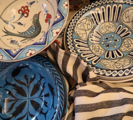 handbemalte Schalen mit Vogel-, Fisch- und Blütenmotiven in Blautönen aus Iznik auf gestreiftem Tuch.