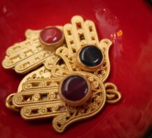 vier goldene handförmige Amulette in einer roten Schale