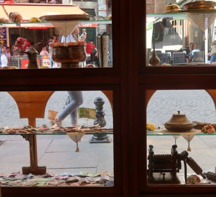 Blick durch ein Schaufenster auf die Strasse, mit Süsswaren und alten Gerätschaften auf Glastablaren